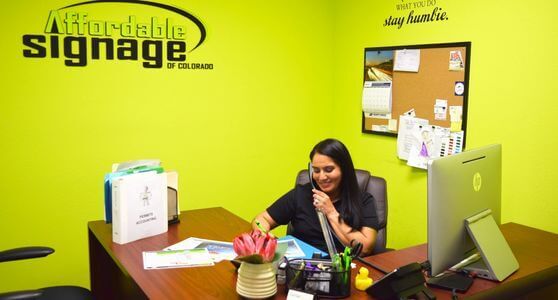 An employee takes a customer call at her desk inside the affordable signage of the Colorado office.