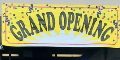 A close-up of the yellow grand opening signage.