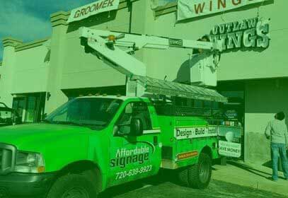 A side view of a green truck of affordable signage of collorado.